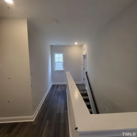 an entryway in a hall with wooden floor and windows