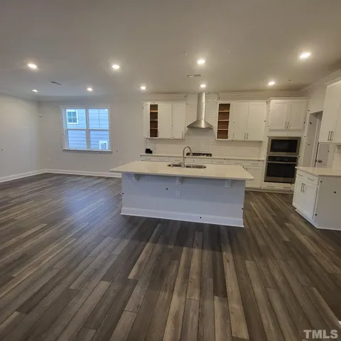 a open kitchen with kitchen island a sink dishwasher a stove and a refrigerator with wooden floor