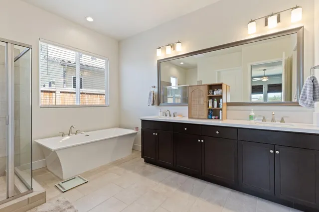 a spacious bathroom with a double vanity sink a mirror and a bathtub