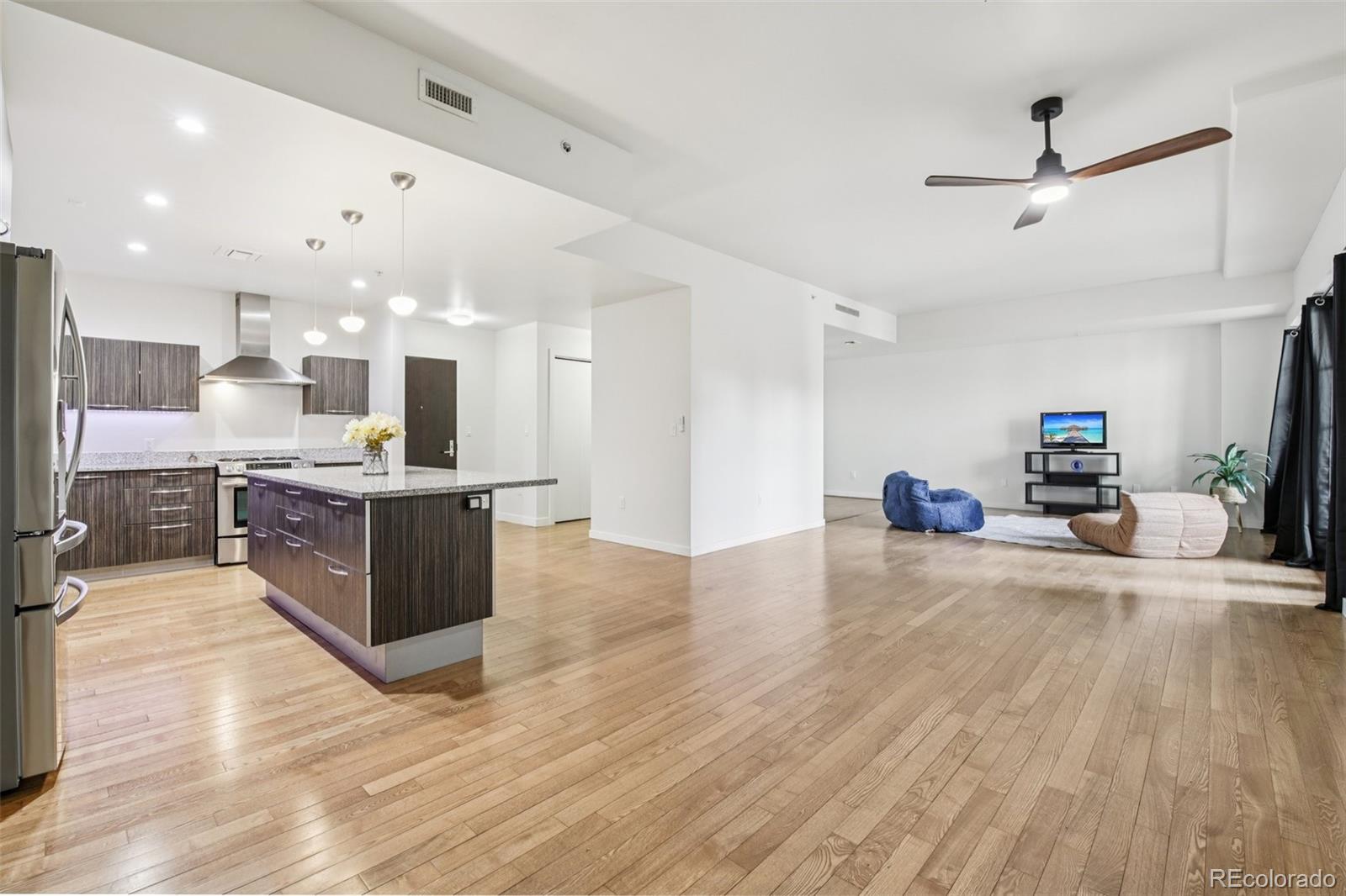 410 Acoma Street, Unit 206 Denver, CO 80204 - Photo 4 of 37 a large kitchen with stainless steel appliances kitchen island granite countertop a large counter top and wooden floors