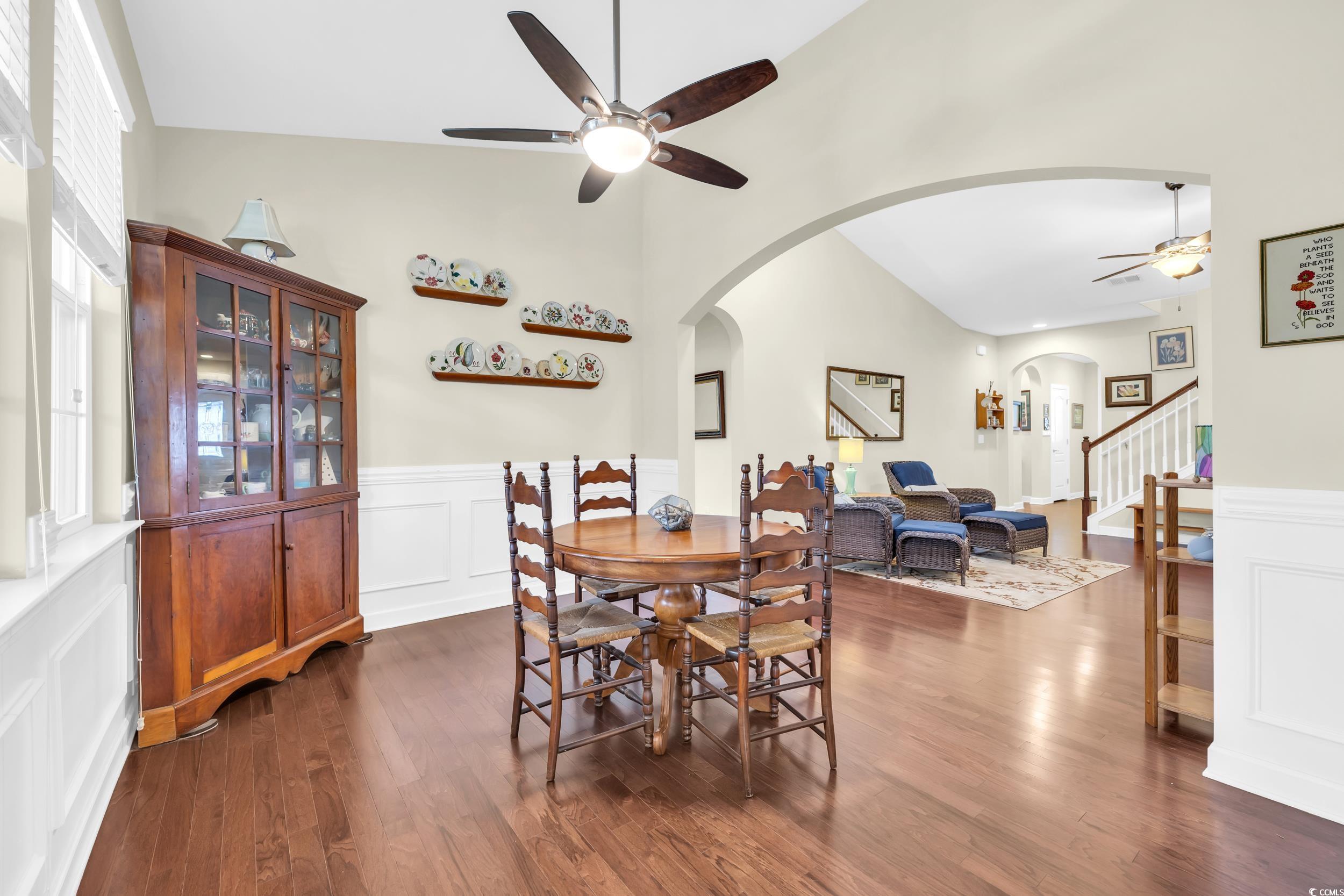 1464 Culbertson Avenue Myrtle Beach, SC 29577 - Photo 8 of 40 Dining area with a ceiling fan, dark wood-style floors, a decorative wall, a wainscoted wall, and stairway