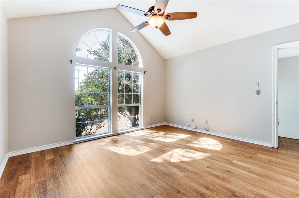 an empty room with wooden floor fan and windows
