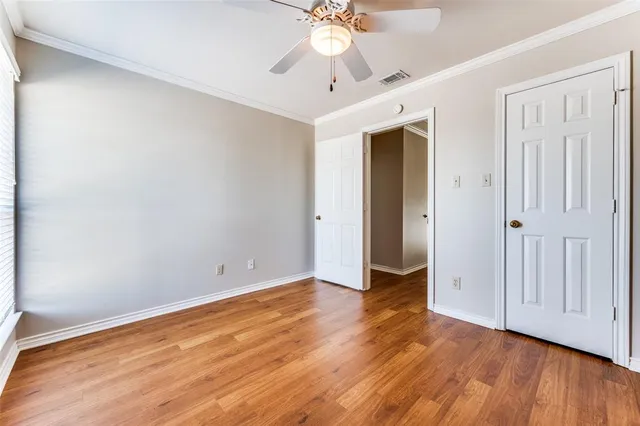 an empty room with wooden floor and ceiling fan