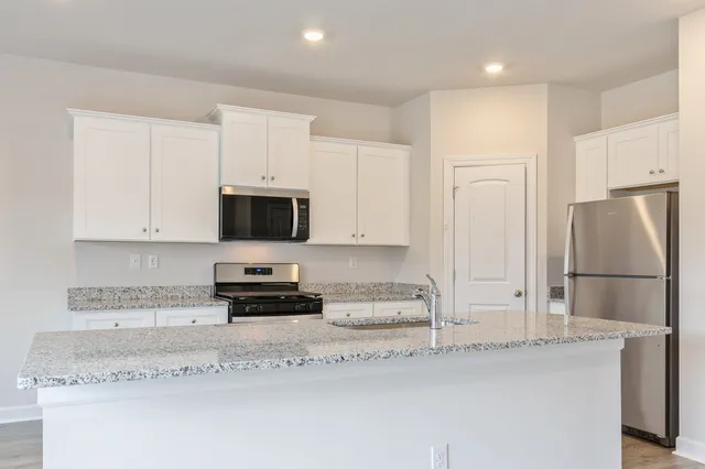 a kitchen with stainless steel appliances granite countertop a refrigerator sink and white cabinets