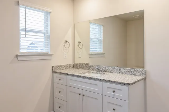 a bathroom with a granite countertop sink and a window