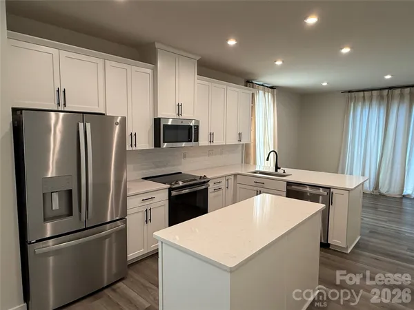 a kitchen with stainless steel appliances granite countertop a refrigerator a stove a sink and a refrigerator