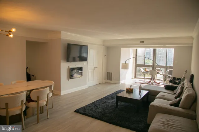 a living room with furniture large windows and wooden floor