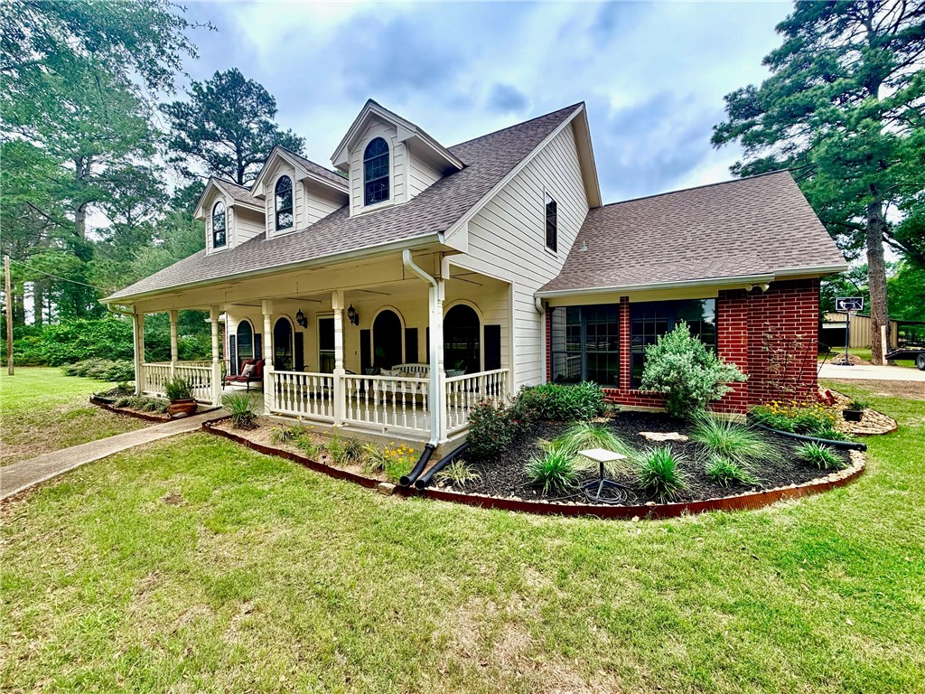 Exterior featuring a full-width covered porch with white railing, brick accents, and multiple dormer windows