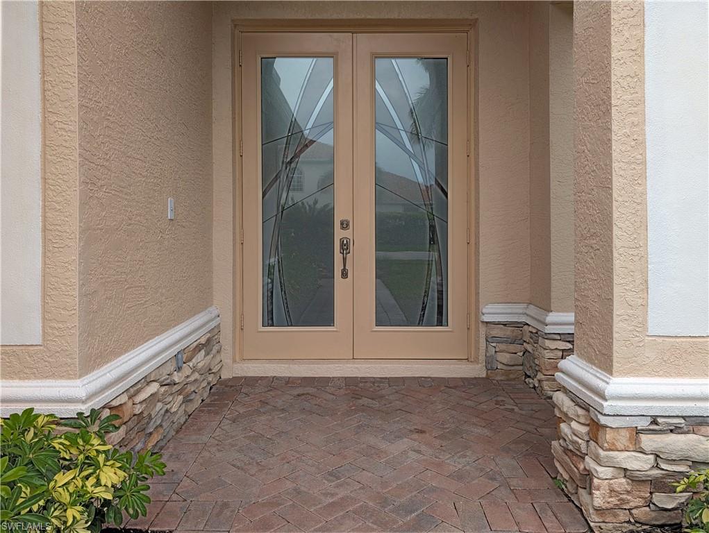 5758 Lago Villaggio Way Naples, FL 34104 - Photo 3 of 42 Property entrance featuring french doors, stone siding, and stucco siding