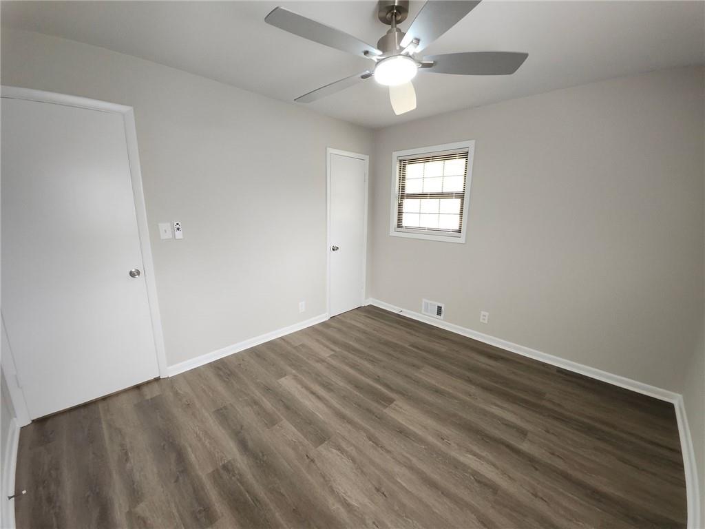 5370 Longmeadow Lane Atlanta, GA 30349 - Photo 12 of 13 an empty room with wooden floor fan and windows