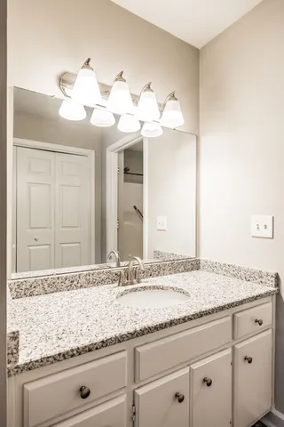 a bathroom with a granite countertop double vanity sink and mirror