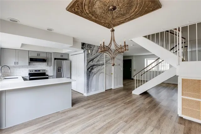 a living room with furniture a chandelier and wooden floor