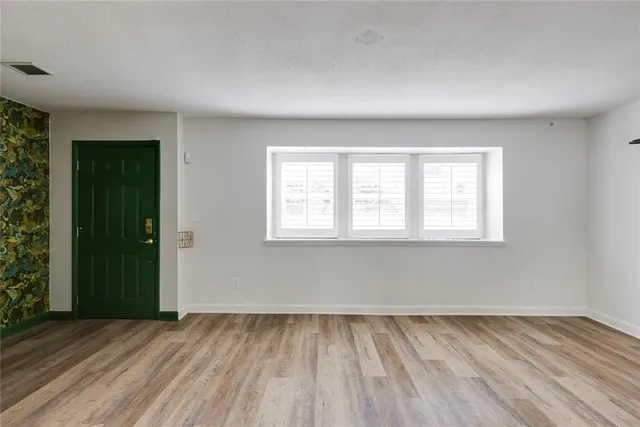 a view of an empty room with wooden floor and stairs