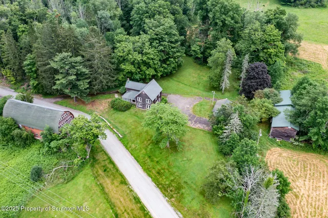 an aerial view of residential house with outdoor space and trees all around