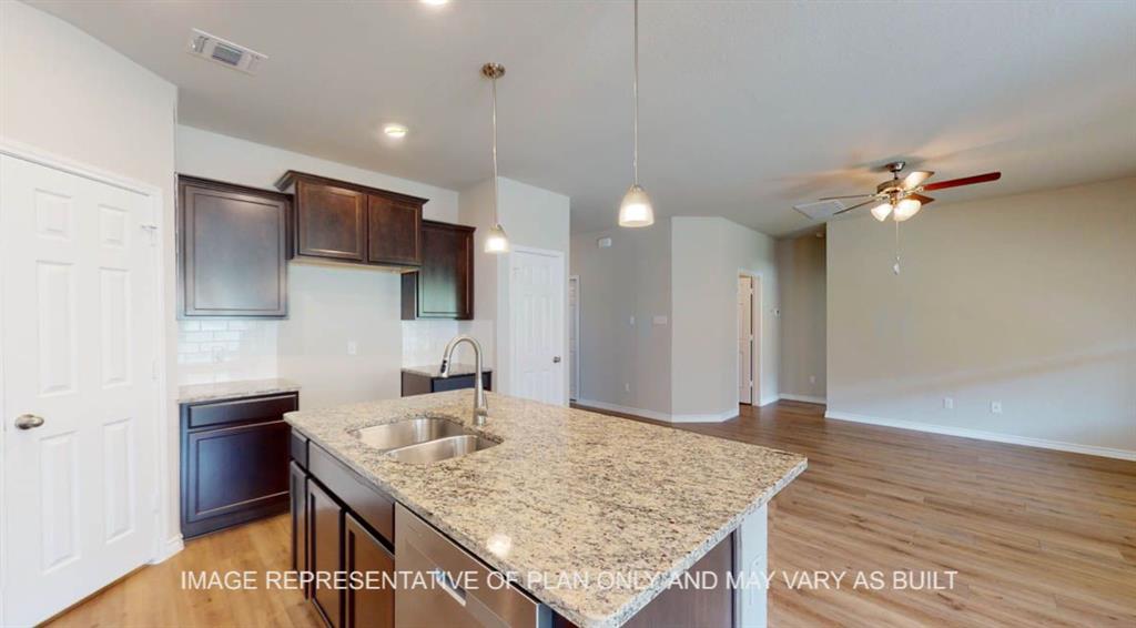 10113 Neptune Court Waco, TX 76708 - Photo 6 of 24 Kitchen island with dual basin sink and granite-style countertop, dark wood-finish cabinetry, subway tile backsplash, stainless steel appliances, and wood-finish flooring