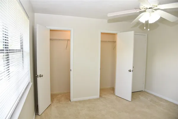 an empty room with a chandelier fan and closet area