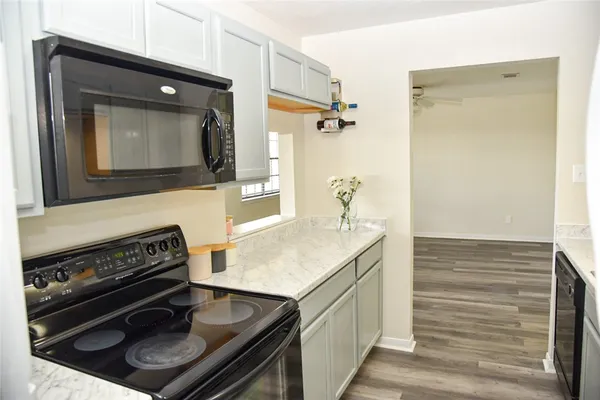 a view of an empty room with wooden floor and a ceiling fan