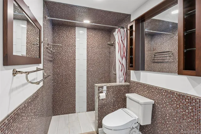 a bathroom with a granite countertop bathtub shower sink mirror and toilet