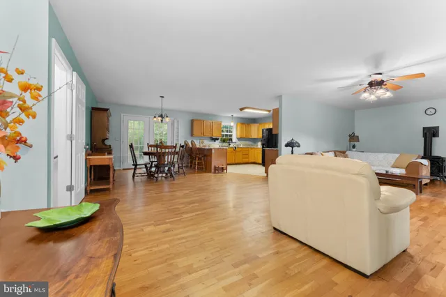 a view of a dining room and livingroom with furniture wooden floor a rug a painting and a chandelier
