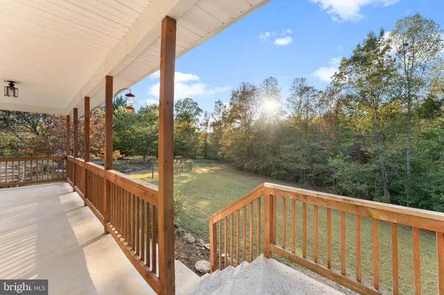 a view of a white house next to a yard with a tree