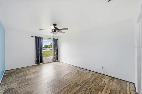 a view of an empty room with a window and wooden floor