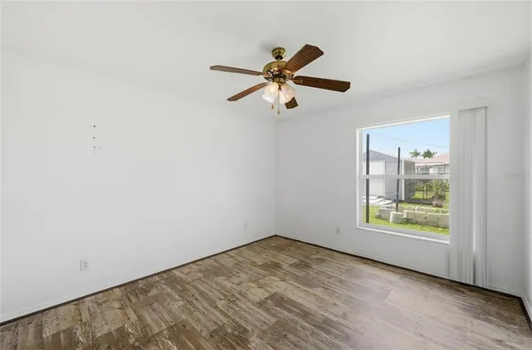 a view of empty room with wooden floor and fan