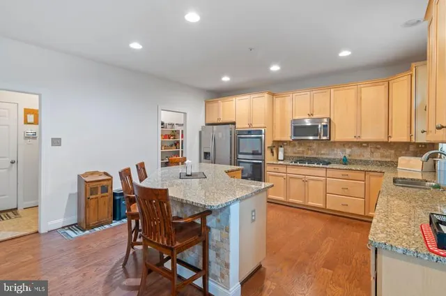 a kitchen with stainless steel appliances granite countertop table chairs sink and cabinets