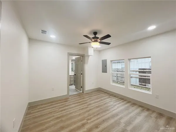 a view of empty room with wooden floor and fan