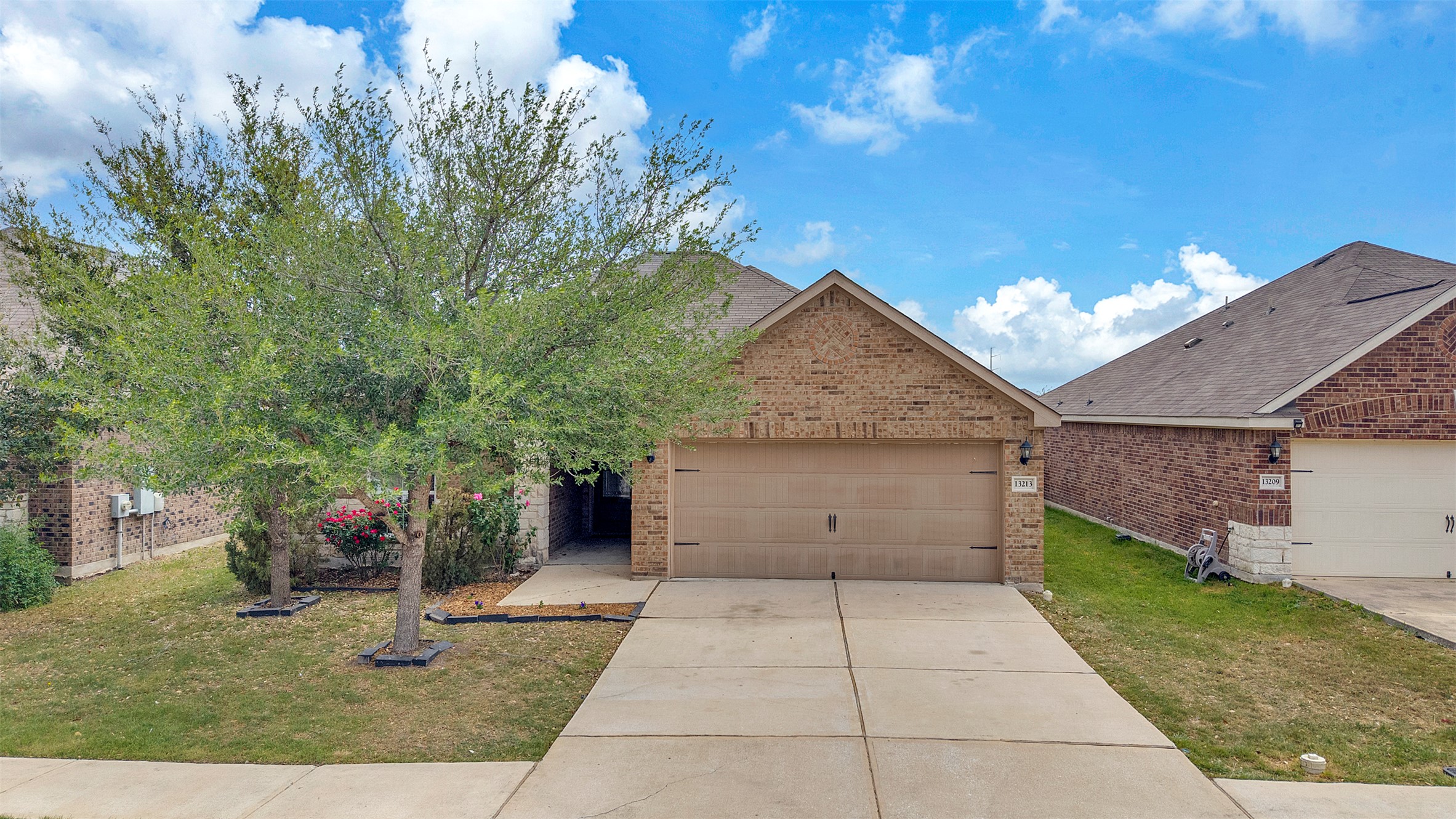 View of front of home with brick siding, a front yard, driveway, and a garage