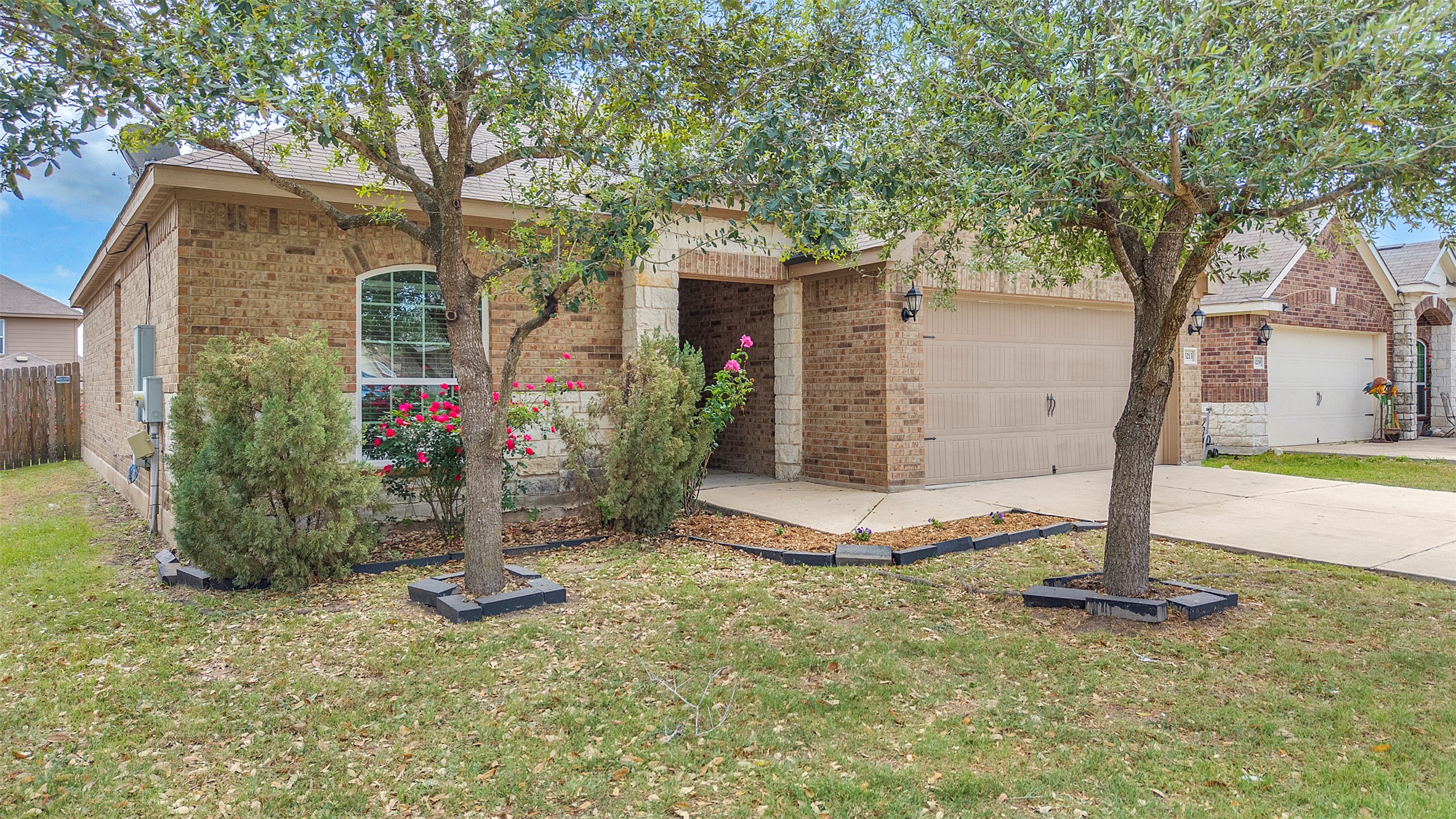 13213 Clara Martin Road Manor, TX 78653 - Photo 2 of 38 View of front of property featuring brick siding, concrete driveway, an attached garage, and a front lawn
