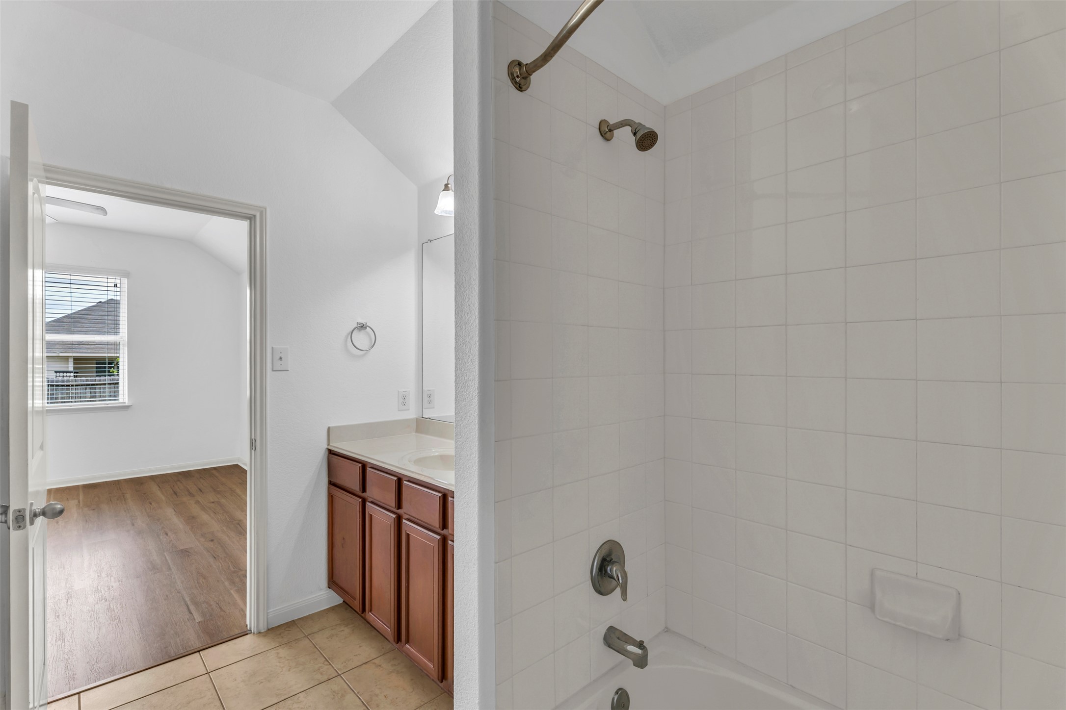 13213 Clara Martin Road Manor, TX 78653 - Photo 24 of 38 Full bath with vanity, washtub / shower combination, light tile patterned flooring, and vaulted ceiling