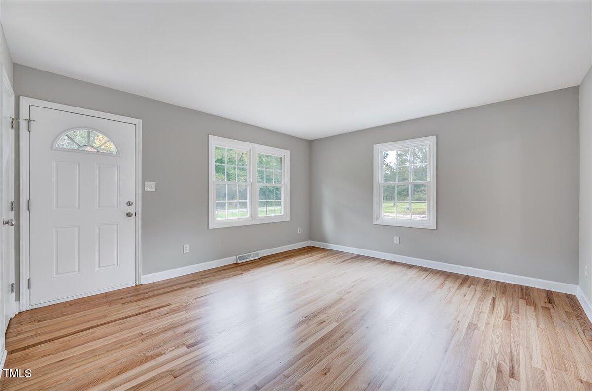 592 Perdues Road Louisburg, NC 27549 - Photo 4 of 27 an empty room with wooden floor and windows