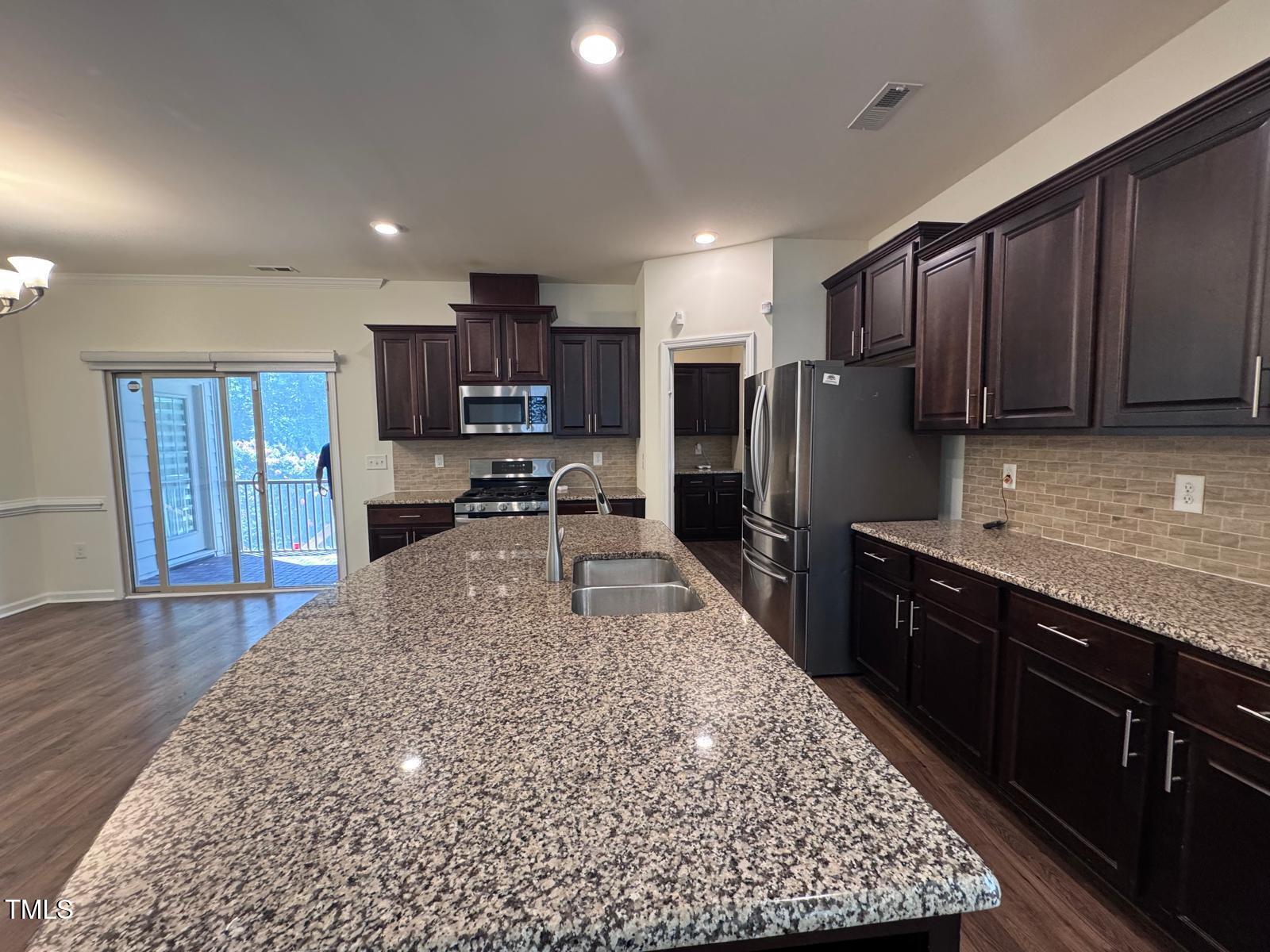1205 Elliott Ridge Lane Morrisville, NC 27560 - Photo 29 of 32 a large kitchen with kitchen island granite countertop wooden cabinets a refrigerator and a sink
