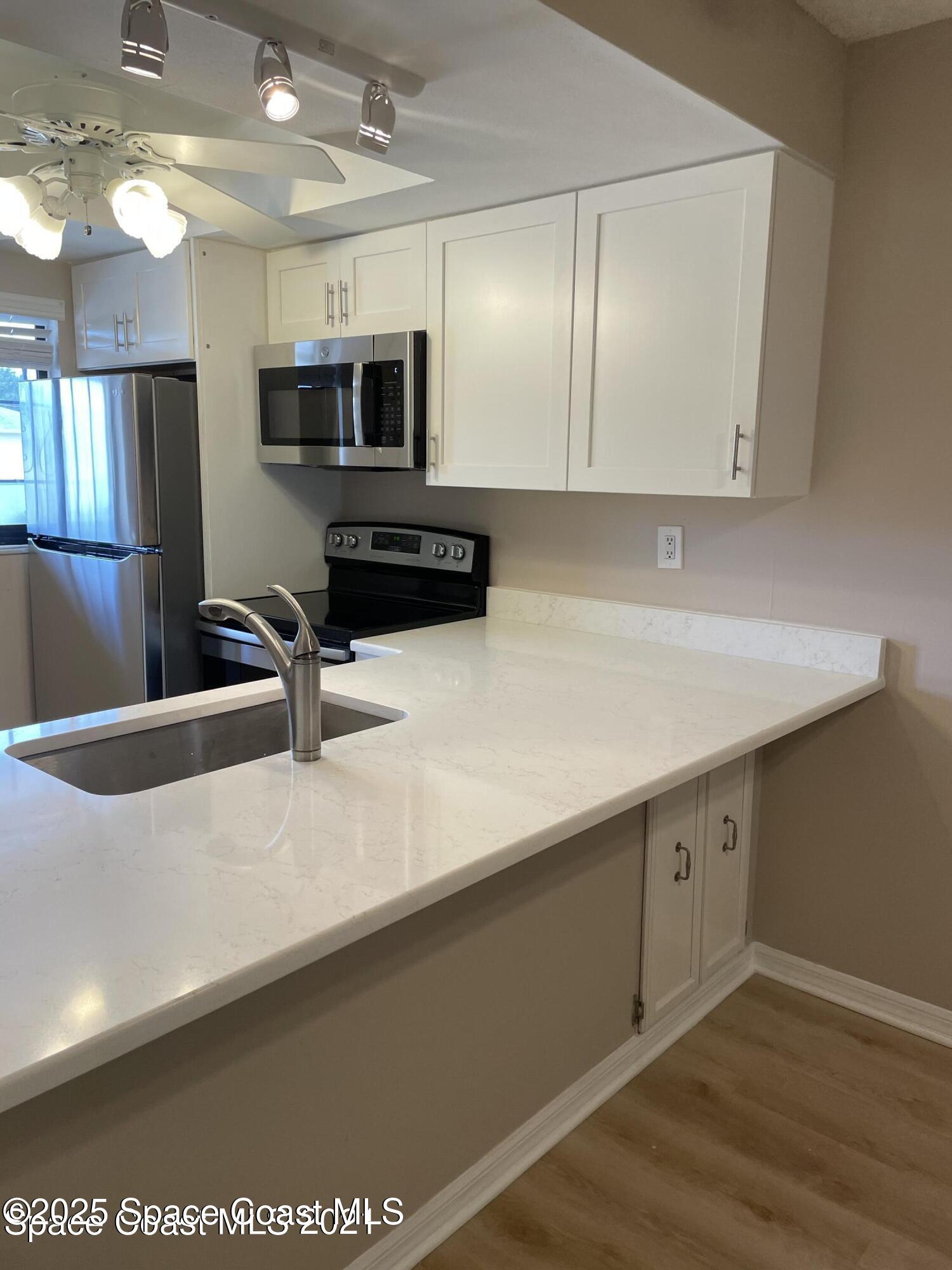 1720 Murrell Road, Unit 217 Rockledge, FL 32955 - Photo 11 of 24 a kitchen with stainless steel appliances a sink a stove and microwave