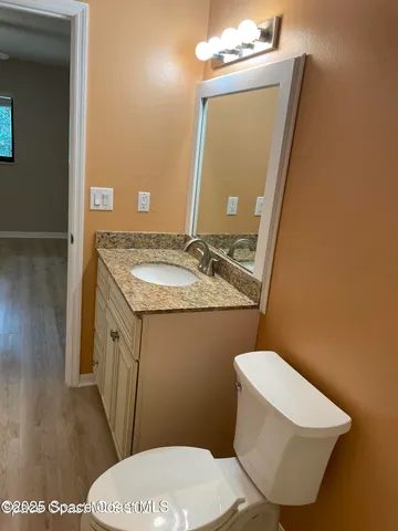 a bathroom with a granite countertop toilet sink and mirror