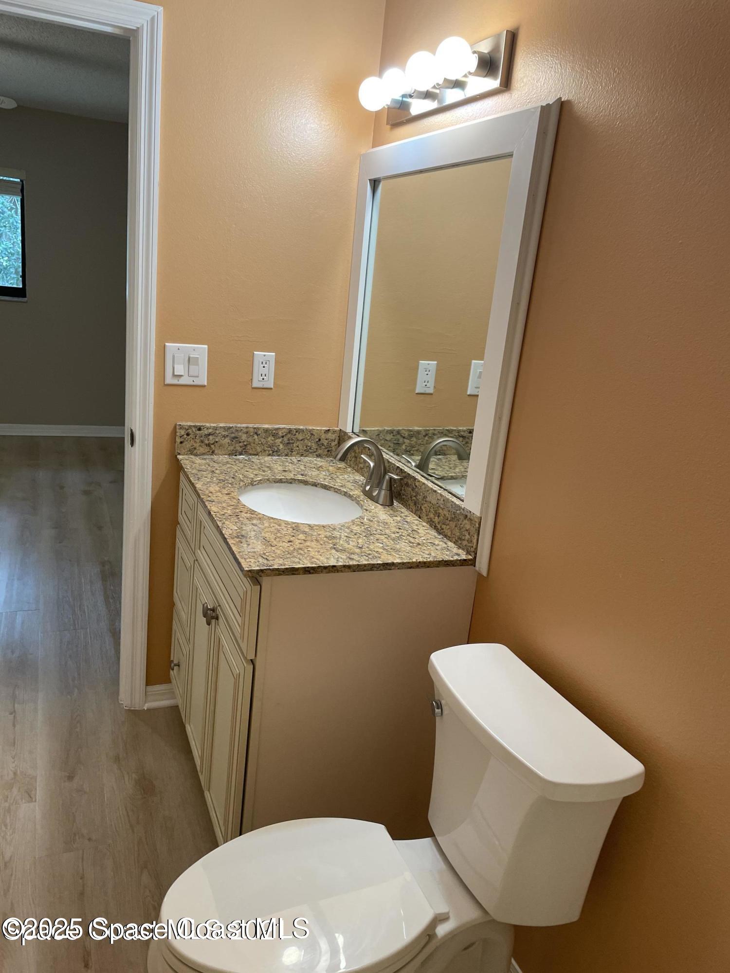 1720 Murrell Road, Unit 217 Rockledge, FL 32955 - Photo 20 of 24 a bathroom with a granite countertop toilet sink and mirror