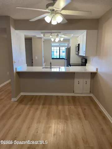 a view of a kitchen with a sink wooden floor and cabinets