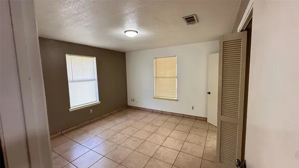 a view of an empty room with window and a bathroom