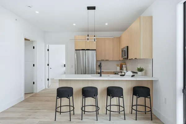 a kitchen with stainless steel appliances a dining table chairs refrigerator and sink