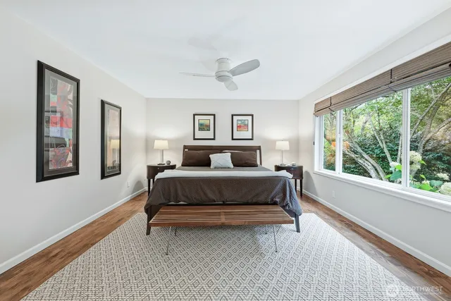 a bedroom with a bed painting and a large window