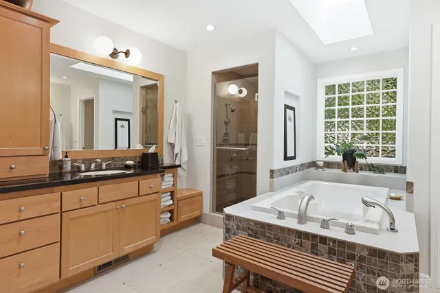 a bathroom with a granite countertop tub a sink and a large mirror
