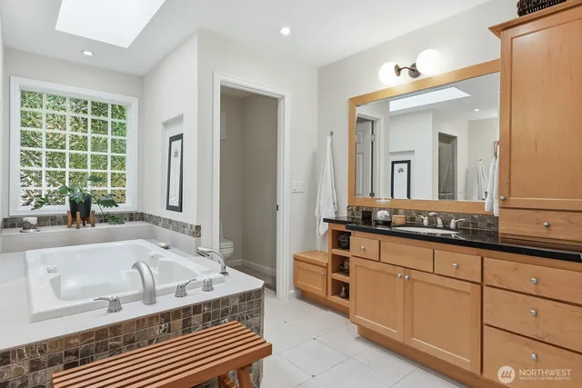 a spacious bathroom with a granite countertop tub a double vanity sink a window and a mirror