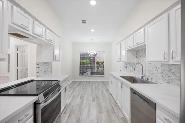 a kitchen with granite countertop a sink stove and cabinets