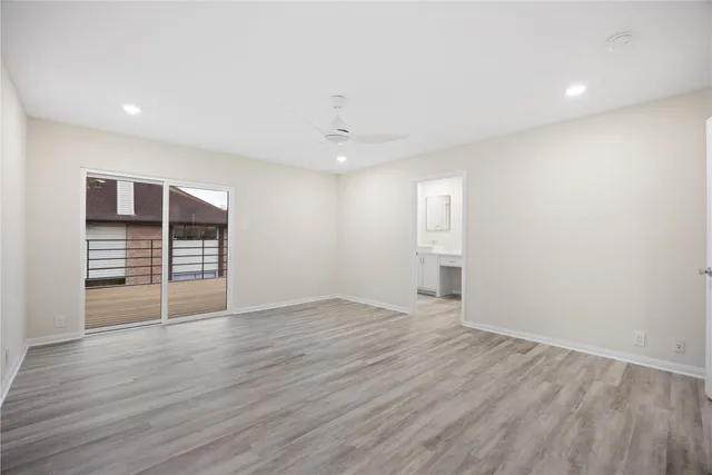 a view of an empty room with wooden floor closet and windows