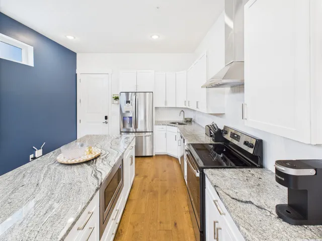 a kitchen with granite countertop a sink stove and refrigerator