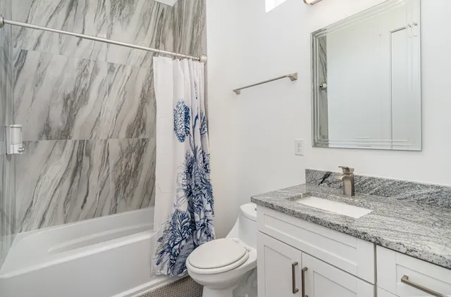 a bathroom with a granite countertop sink toilet and shower