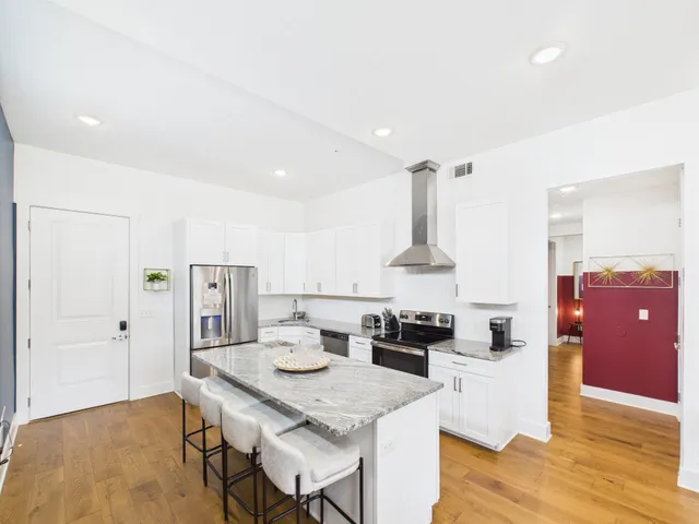 a kitchen with stainless steel appliances kitchen island granite countertop a table chairs and a refrigerator
