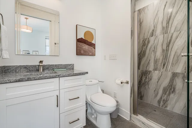 a bathroom with a granite countertop toilet sink and mirror
