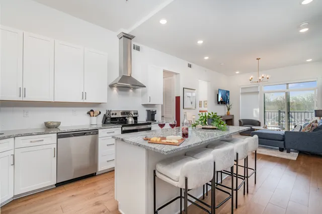 a kitchen with stainless steel appliances kitchen island granite countertop a stove a sink and a refrigerator