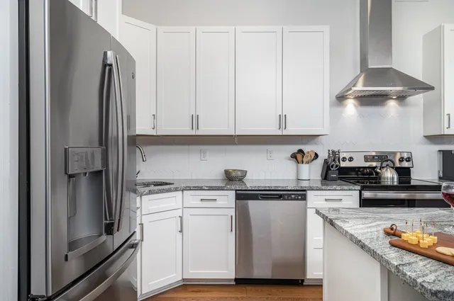 a kitchen with stainless steel appliances granite countertop a refrigerator and white cabinets